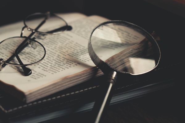 Glasses and magnifying glass on top of an open book