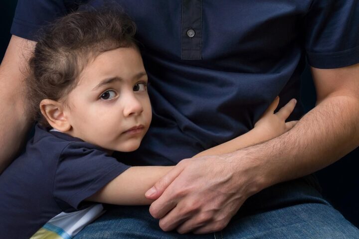 Small child standing with arms wrapped around seated parent’s waist; occasion for a guardian ad litem appointment.