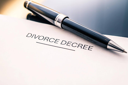 A pen and divorce papers reading “divorce decree” sitting on a desk.