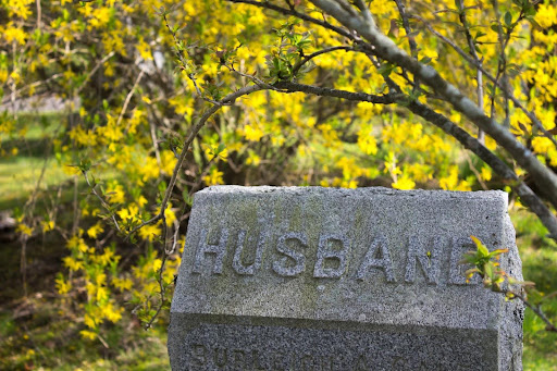 A concrete gravestone with the word “Husband” engraved on it. What happens when a spouse dies during divorce depends on multiple factors.