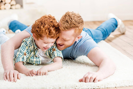 A father and son playing together on the floor after determining a visitation schedule.