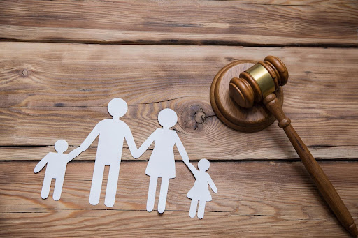 Paper cutouts of a family with kids on a table with a gavel. Concept for family law and child custody.