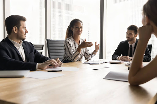 Spouses represented by attorneys discussing their family law dispute at a conference table while a mediator looks on; who pays for mediation in family law disputes may be determined by agreement or court order.