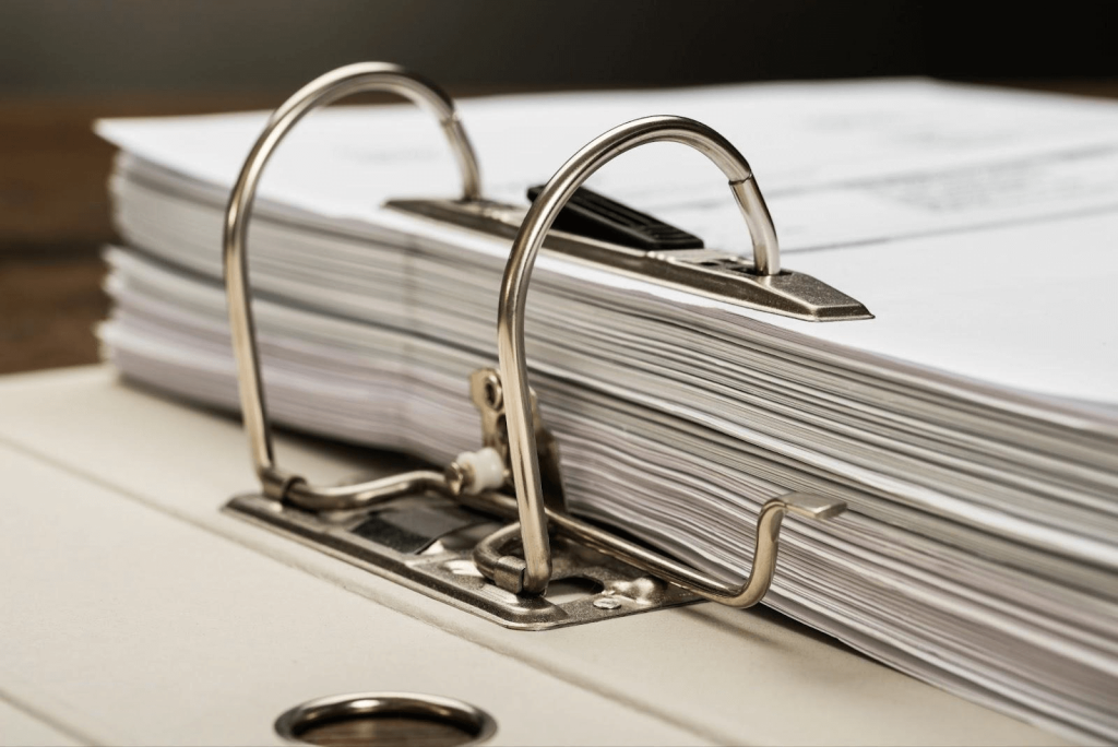 A stack of white papers sits inside a large binder; a skilled lawyer can provide strategies for collecting unpaid contract payments.