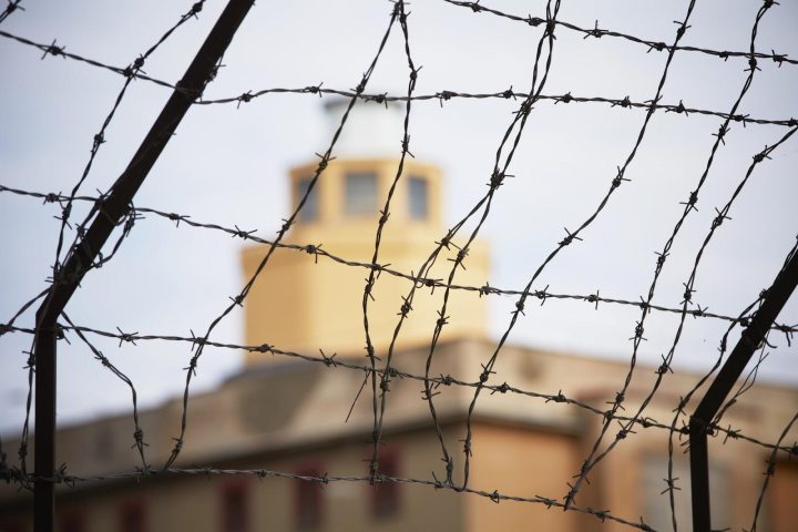 Barbed wire fence with a building in the distant background; trespassing and other forms of unauthorized entry may be violations of landowner rights.
