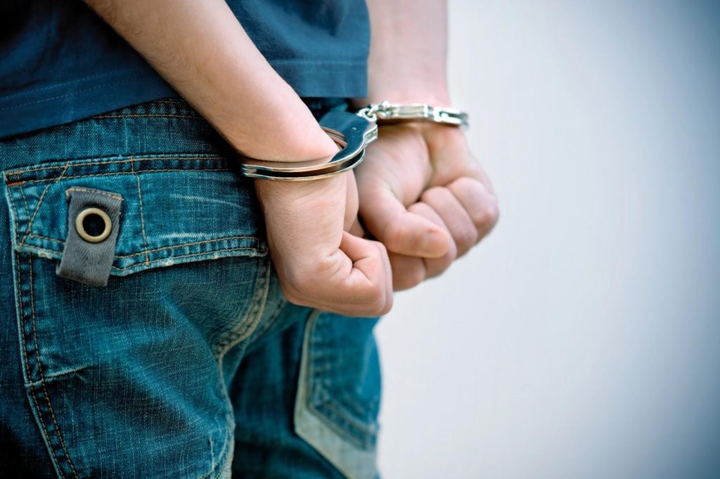 An individual in handcuffs after an arrest, illustrating how criminal charges can lead to plea bargains in court.